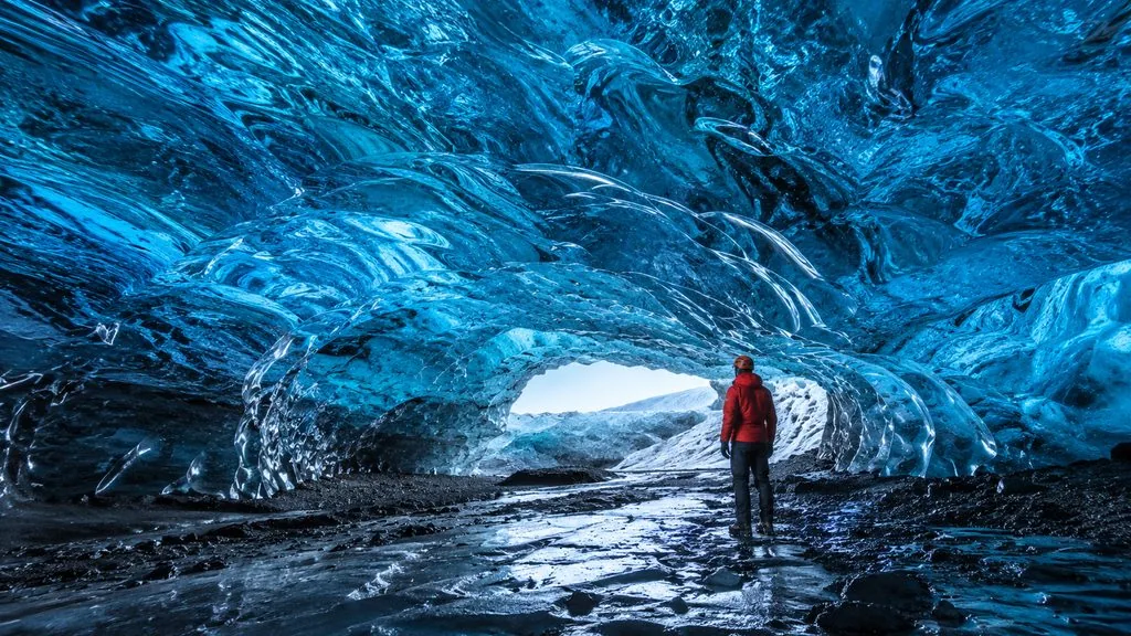 Interior of a Vatnajokull crystal cave, bright blue ice reaching overhead
